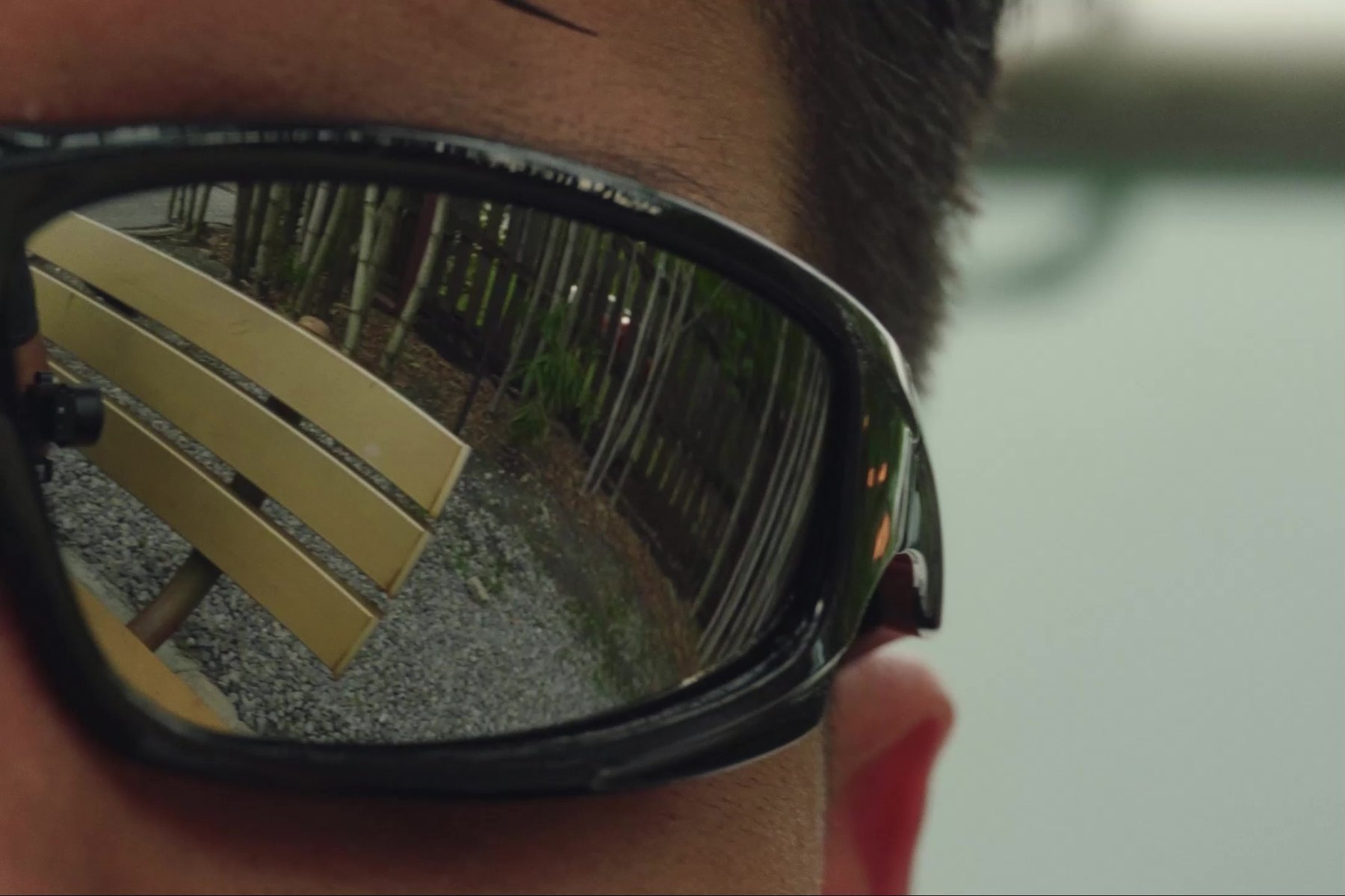 Close up of Diego Leras wearing sunglasses, a park bench and bamboo reflected in the lens